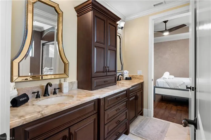 Bathroom featuring ornamental molding, ensuite bath, double vanity, a ceiling fan, and a shower stall