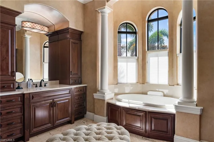 Full bathroom featuring a bath, ornate columns, vanity, and crown molding