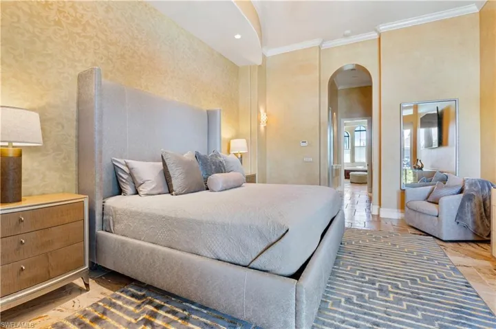 Bedroom featuring arched walkways, ornamental molding, recessed lighting, and stone tile flooring