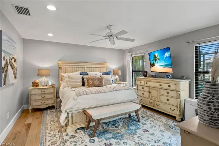 Primary Bedroom featuring light hardwood / wood-style flooring a, abundant light and sliders to the outdoor pool area!