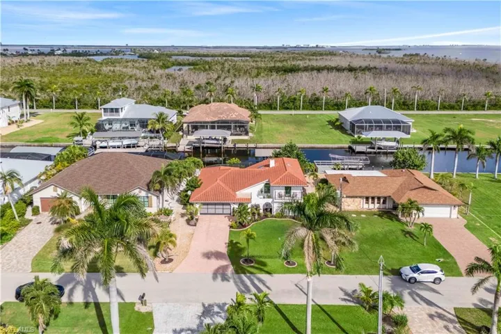 Aerial view highlighting the front of the home, showcasing its curb appeal, landscaped yard, and driveway, set within a picturesque neighborhood.