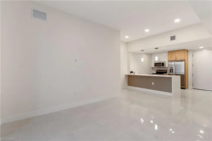 The open-concept living area combines stylish tile floors with 9–10 foot ceilings and impact-resistant windows, filling the space with light and an inviting sense of openness.