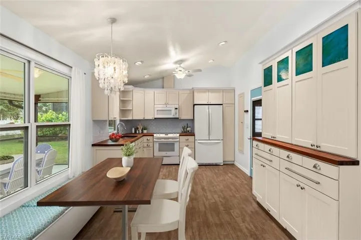 Kitchen featuring lofted ceiling, sink, decorative backsplash, hanging light fixtures, and white appliances