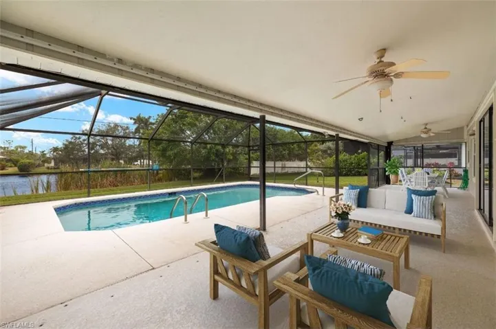 View of swimming pool with a lanai, ceiling fan, outdoor lounge area, a patio, and a water view