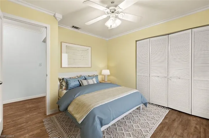 Bedroom with dark hardwood / wood-style flooring, ornamental molding, a closet, and ceiling fan
