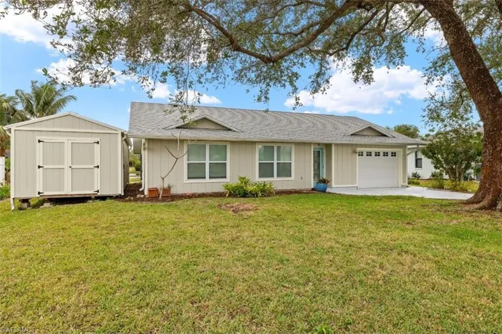 Single story home with a garage, a front lawn, and a storage unit