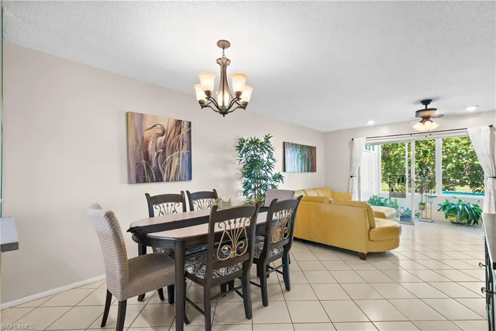Tiled dining room featuring a textured ceiling and ceiling fan with notable chandelier