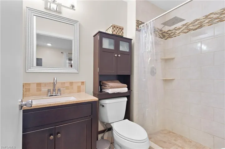 Bathroom with vanity, curtained shower, and toilet