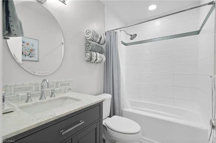Full bathroom with toilet, shower / bath combination with curtain, and oversized vanity