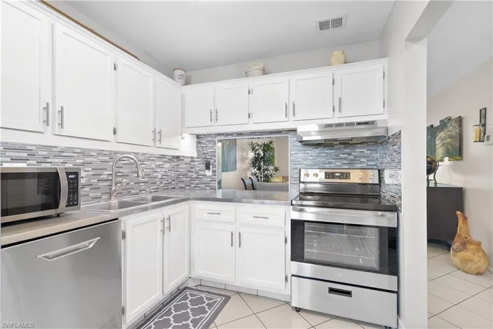 Kitchen featuring appliances with stainless steel finishes, sink, tasteful backsplash, and light tile floors
