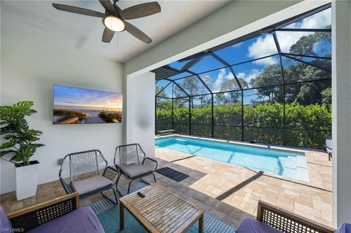 Screened-in outdoor living space featuring a ceiling fan and wall-mounted television