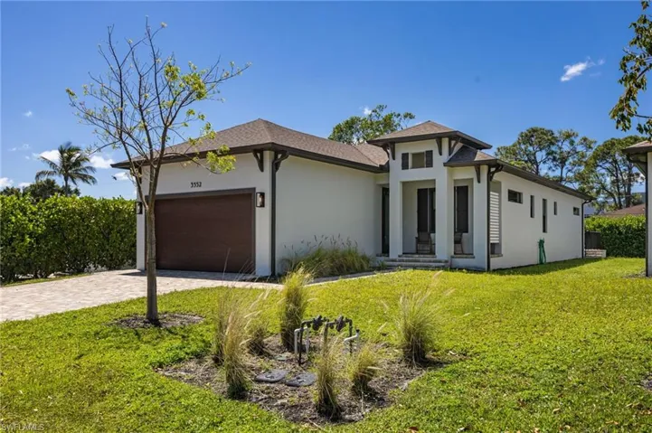 Contemporary stucco exterior with dark trim accents, a paver driveway, and a coordinating dark wood-finish garage door