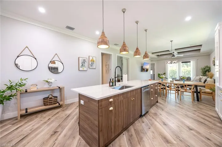 Kitchen island with wood-finish cabinetry, white countertop, and integrated stainless steel dishwasher