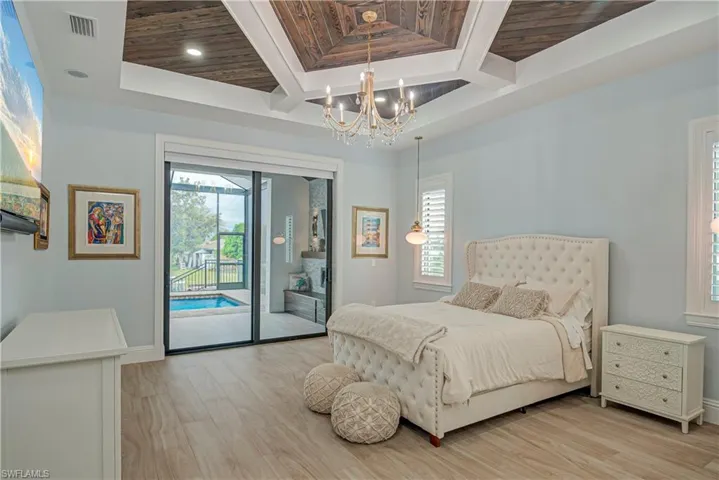 Bedroom featuring light wood-style floors, access to outside, a chandelier, multiple windows, and a wooden ceiling with exposed beams