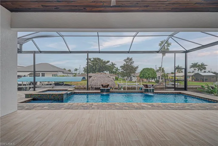 View of pool with a sunroom, a lanai, a pool with connected hot tub, and a patio area