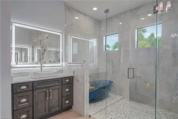 Bathroom featuring vanity, a marble finish shower, and recessed lighting