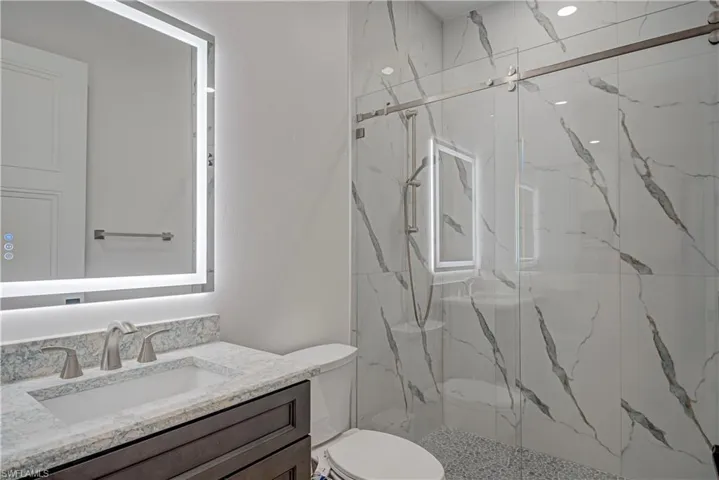 Bathroom featuring vanity and a marble finish shower