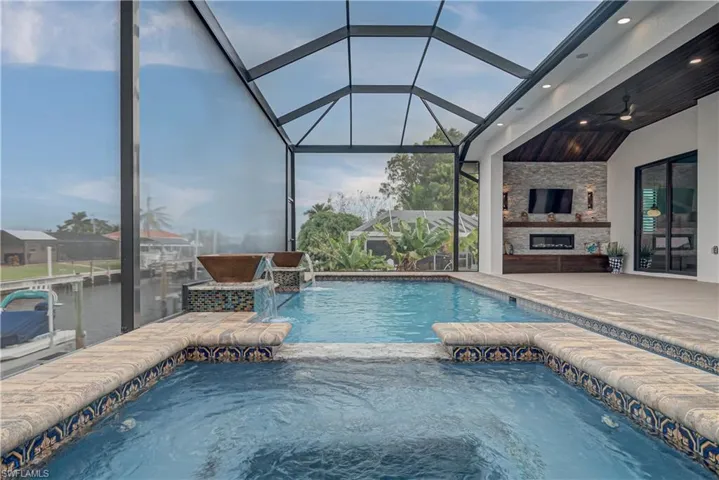 View of swimming pool with a lanai, a sunroom, a patio area, and an outdoor stone fireplace