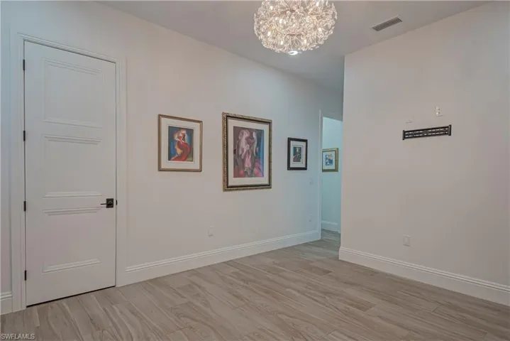 Empty room with a chandelier and light wood-style flooring