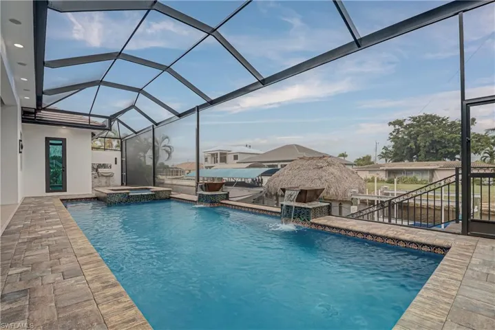 View of swimming pool with glass enclosure, a sunroom, a patio area, and a pool with connected hot tub