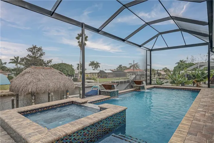 View of swimming pool featuring a sunroom, a lanai, a pool with connected hot tub, boat lift, and a boat dock