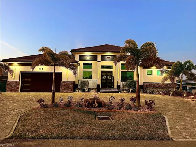 View of front facade featuring stucco siding, decorative driveway, stone siding, a lawn, and a garage
