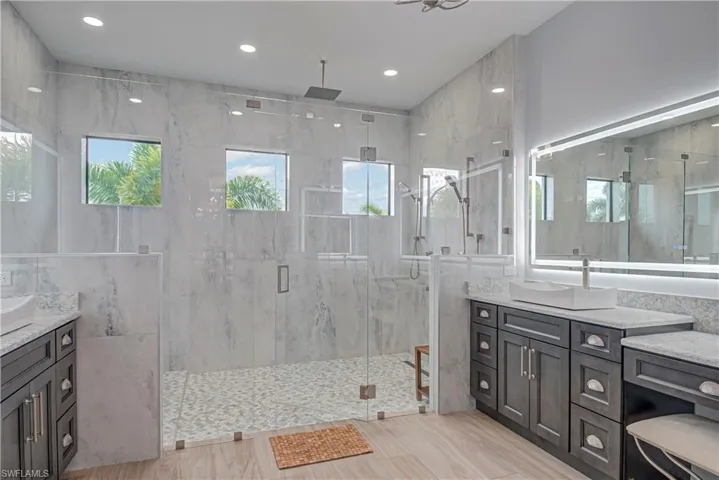Full bath with vanity, a marble finish shower, and recessed lighting