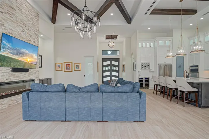 Living area with a chandelier, a towering ceiling, beamed ceiling, a fireplace, and light wood finished floors