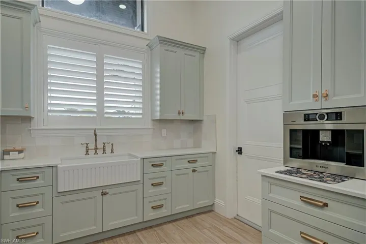 Kitchen with light wood-style flooring, oven, tasteful backsplash, and light stone countertops