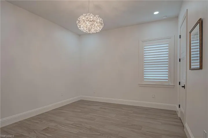 Spare room with light wood finished floors, a chandelier, and recessed lighting