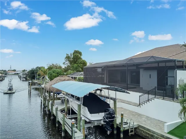 Dock area with boat lift, a water view, a lanai, and a sunroom