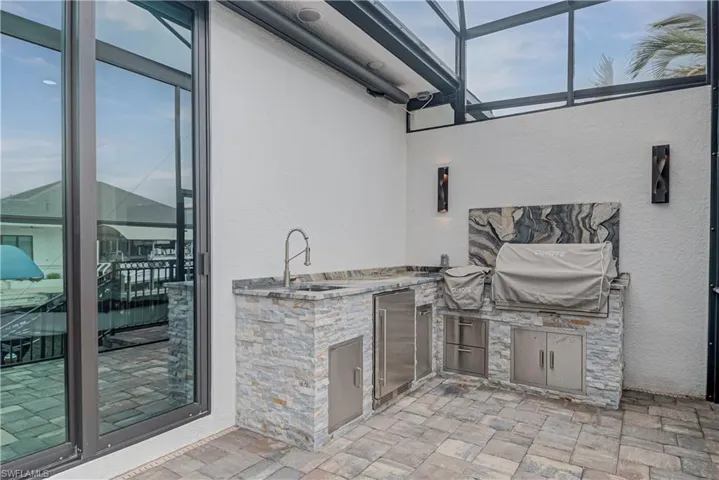 View of patio / terrace featuring a sunroom, a lanai, and exterior kitchen