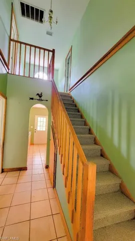 Stairway with a high ceiling, a chandelier, and tile patterned floors
