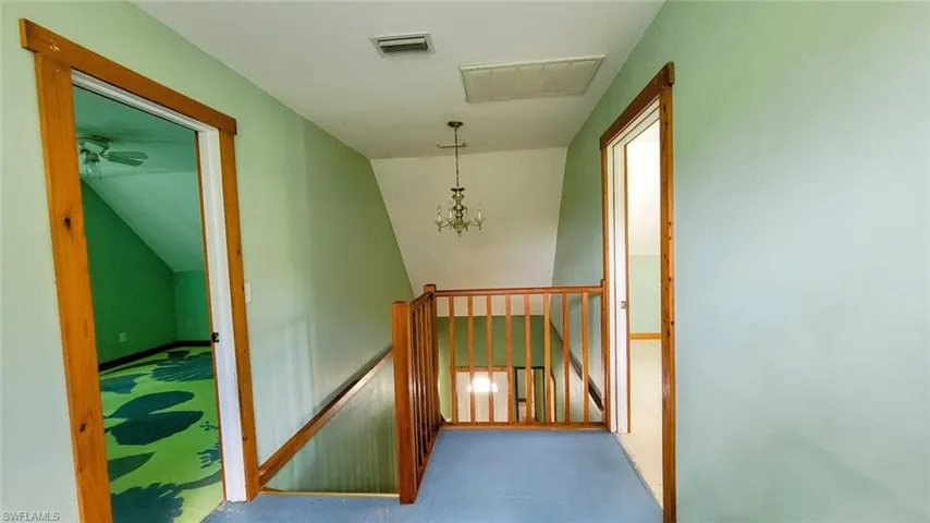 Corridor featuring an inviting chandelier and vaulted ceiling