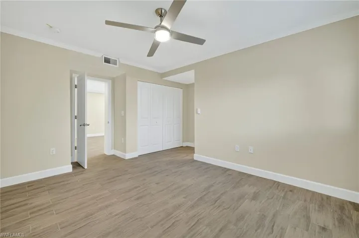 Unfurnished bedroom featuring ornamental molding, light wood-type flooring, a closet, and a ceiling fan