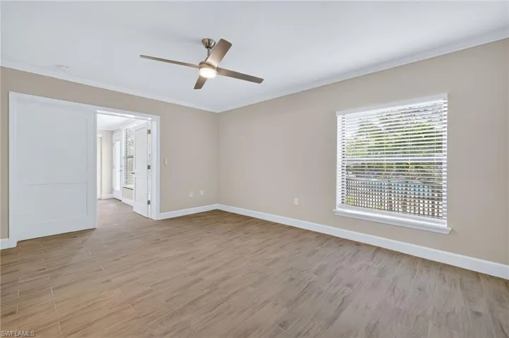 Spare room featuring light wood-style floors, crown molding, plenty of natural light, and a ceiling fan