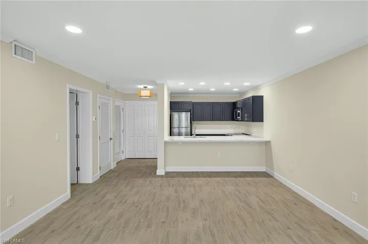 Unfurnished living room featuring crown molding, light wood-type flooring, and recessed lighting