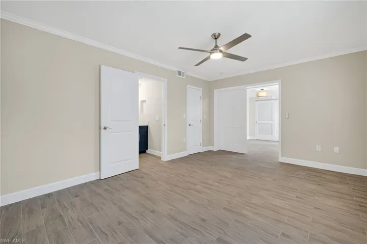 Unfurnished bedroom with ornamental molding, ceiling fan, light wood-style flooring, and ensuite bathroom