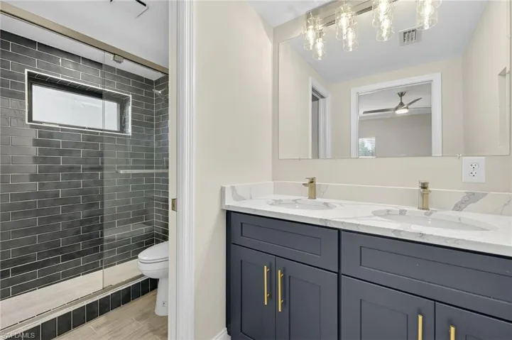 Bathroom featuring double vanity and tiled shower