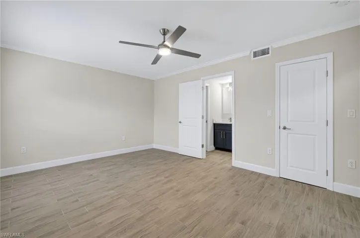 Unfurnished bedroom with crown molding, light wood-type flooring, ceiling fan, and connected bathroom