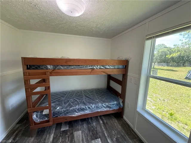 Wood-finish flooring with white wall paneling, a large window, and a built-in light fixture