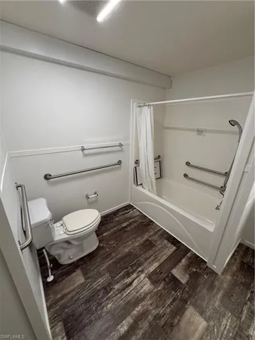 Tub/shower combination with grab bars and wood-finish flooring