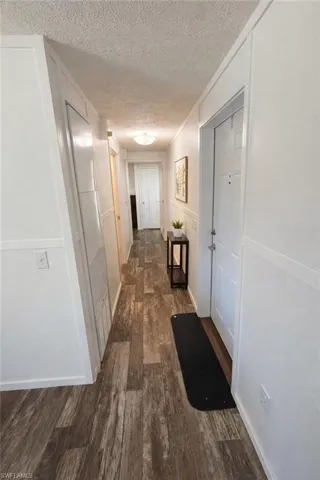 Hallway featuring wood-finish flooring, white paneling, and an overhead flush-mount light fixture