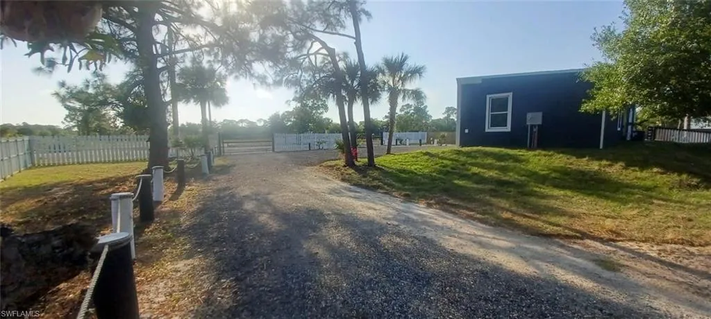 View of road with gravel driveway and a gate