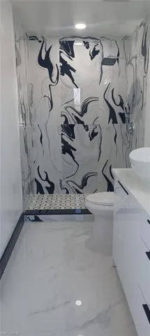 Bathroom featuring walk in shower, vanity, and toilet