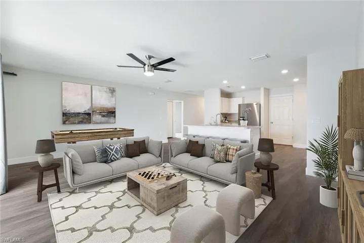 Living room with ceiling fan, light wood-type flooring, and sink