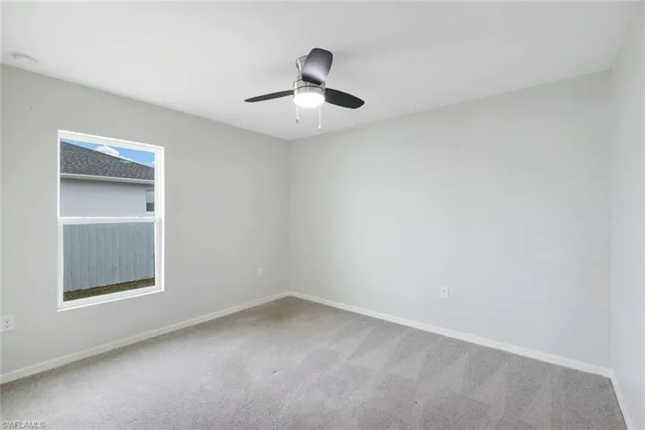 Carpeted spare room featuring ceiling fan