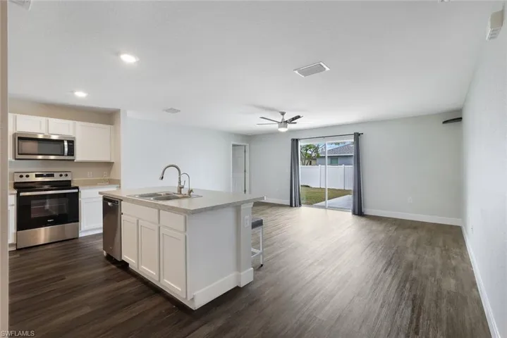 Kitchen featuring appliances with stainless steel finishes, a kitchen island with sink, sink, dark hardwood / wood-style floors, and white cabinetry
