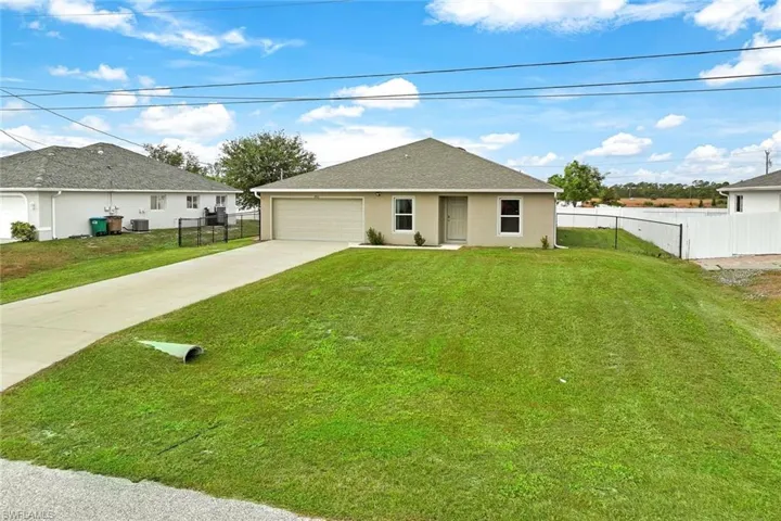 View of front facade featuring a front yard, a garage, and cooling unit