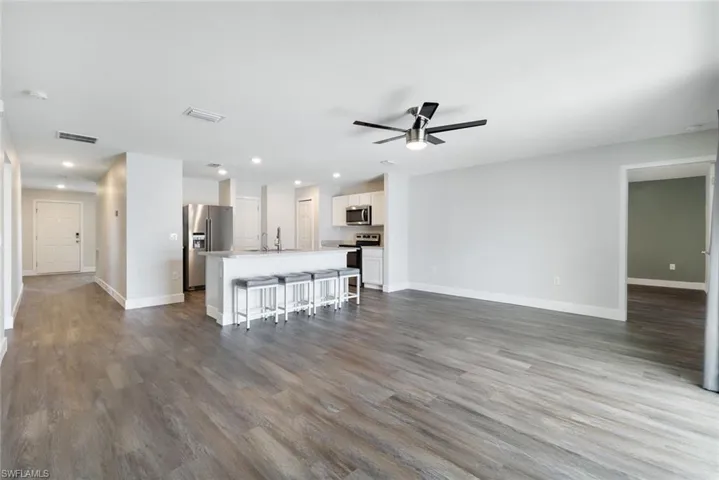 Unfurnished living room featuring ceiling fan, sink, and wood-type flooring